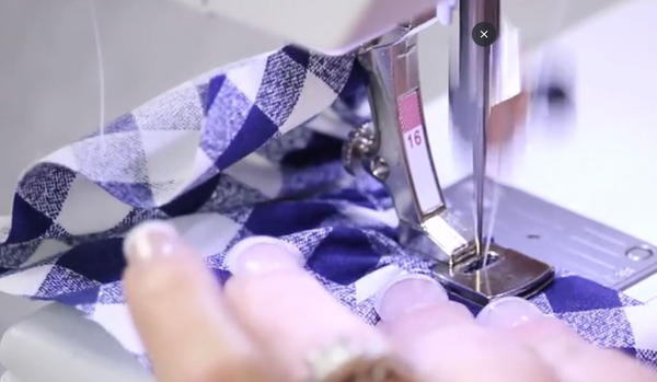 Image shows the gathering foot ruffle method of gathering fabric being sewn on a sewing machine.