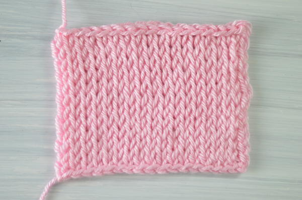 Image shows a rectangle swatch in pink showing the Tunisian crochet knit stitch.