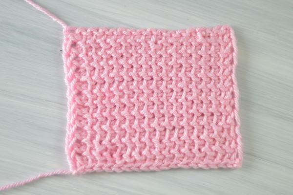 Image shows a rectangle swatch in pink showing the Tunisian crochet purl stitch.