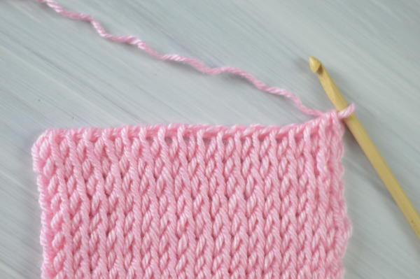 Image shows a pink swatch showing the last row of Tunisian crochet.