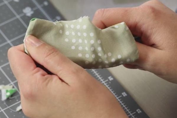Image shows hands turning out the sewn pin cushion.