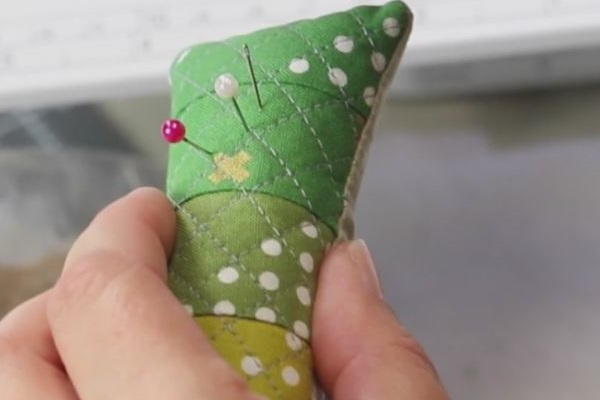 Image shows a hand holding the finished pin cushion with pins in it.