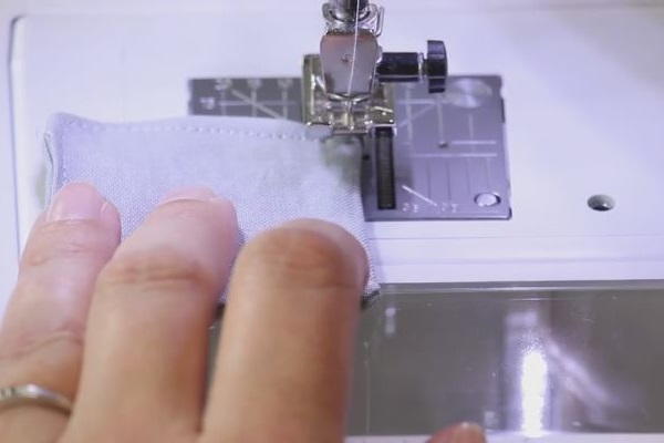 Image shows a close up of the fabric square being sewn up completely with a machine.