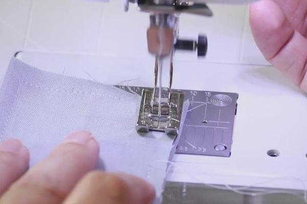 Image shows a close up of the fabric pieces being sewn together with a machine.
