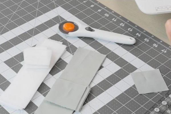 Image shows a cutting board with strips of fabric and a rotary cutter sitting on top.