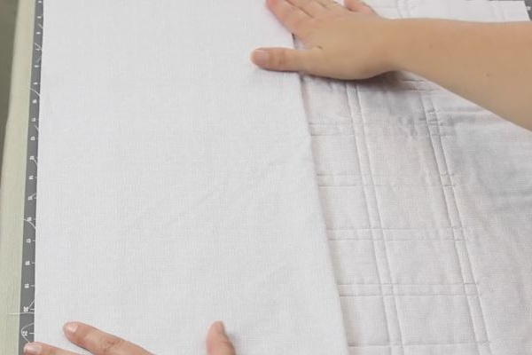 Image shows hands adding a pocket to the back of the main light fabric calendar piece.