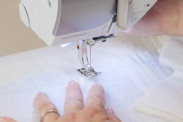 Image shows the Velcro being sewn with a machine to the piece of light fabric.