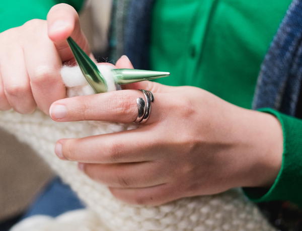 Image shows a close-up of a person knitting.