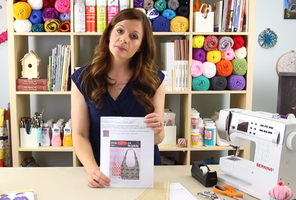 Image shows Angel (woman) in a craft room holding a printed out digital pattern.