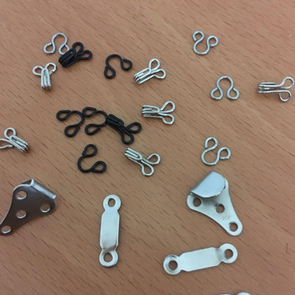 Image shows a variety of a hook and eye fasteners on a table.