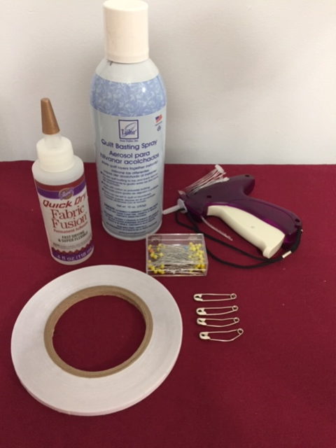 Image shows a set of alternative tools for tacking including fabric fusion, basting spray, tape, safety pins, straight pins, and a glue gun on a red background.