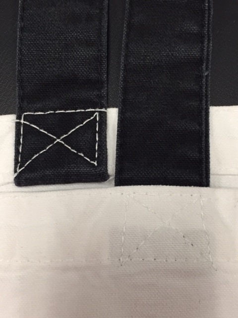 Image shows a close-up of tote bag handles to visually explain cross-tacking on tote handles.