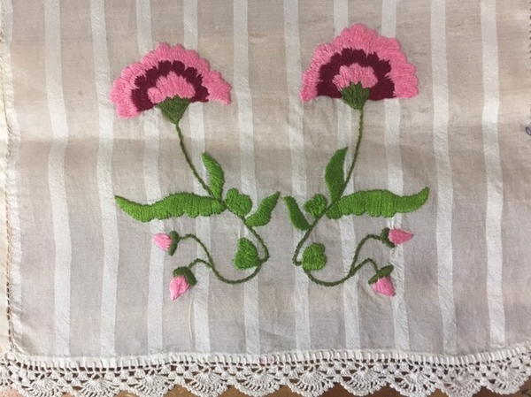 Image shows a tea towel with embroidered flowers on the front.
