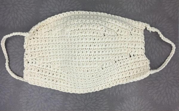Image shows a white crochet mask on a gray background.