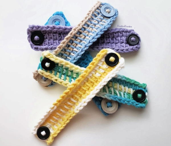 Image shows five different crochet ear savers (mask mates) piled upon one another.