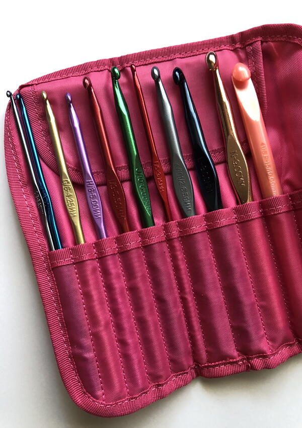 Image shows an open pink crochet hook case with hooks sitting inside.