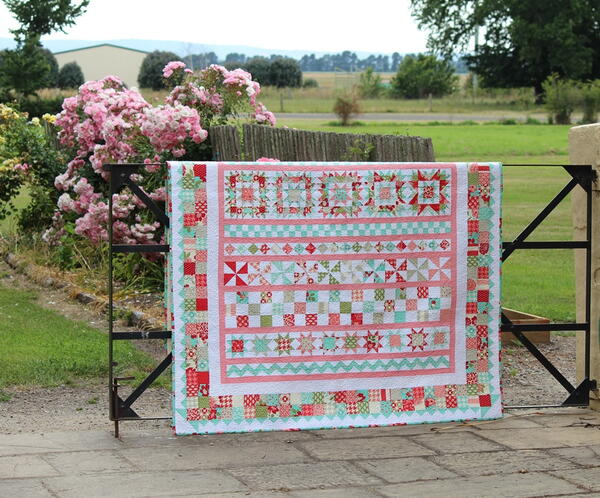 Image shows a quilt hung over a gate outside.