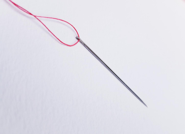 Image shows the threaded needle on a light background.