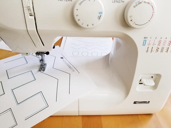 Image shows a sewing machine with a practice sheet being sewn.