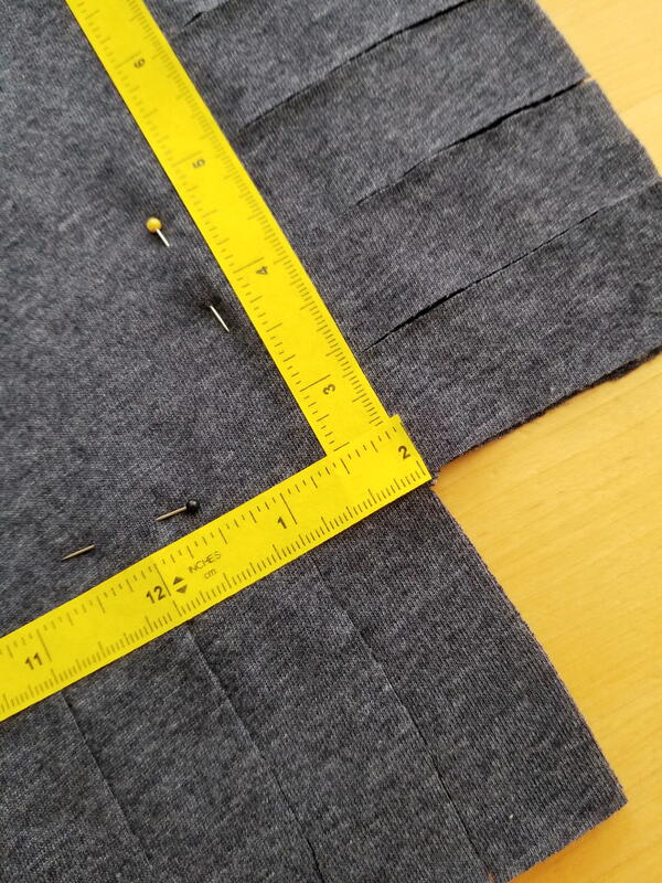 Image shows a close-up of the shirt with 1" strips cut. There's ruler tape and pins on the shirt.