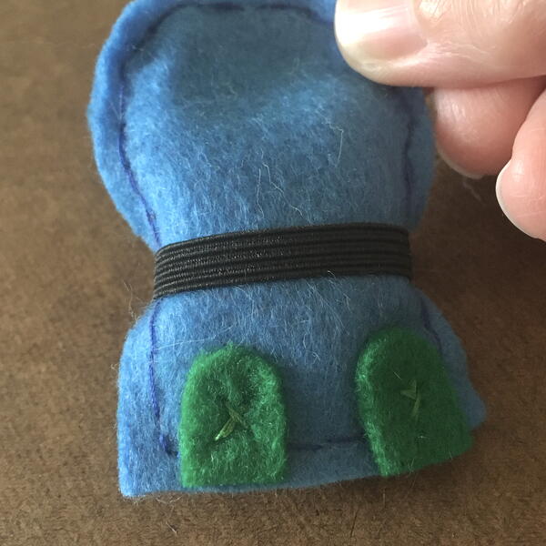 Image shows the blue felt body, green shoes, and black belt attached for the DIY Gnome Ornament.