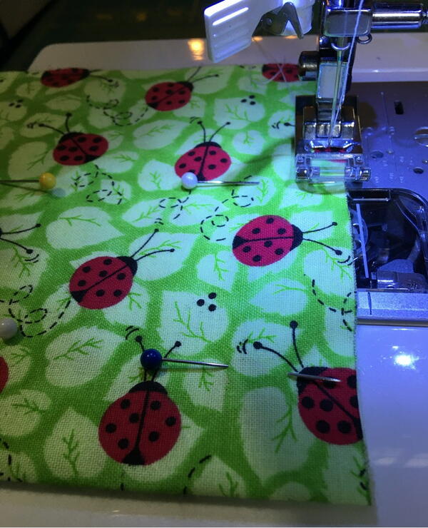 Image shows a sewing machine sewing the pinned fabric for how to sew a drawstring bag in minutes.