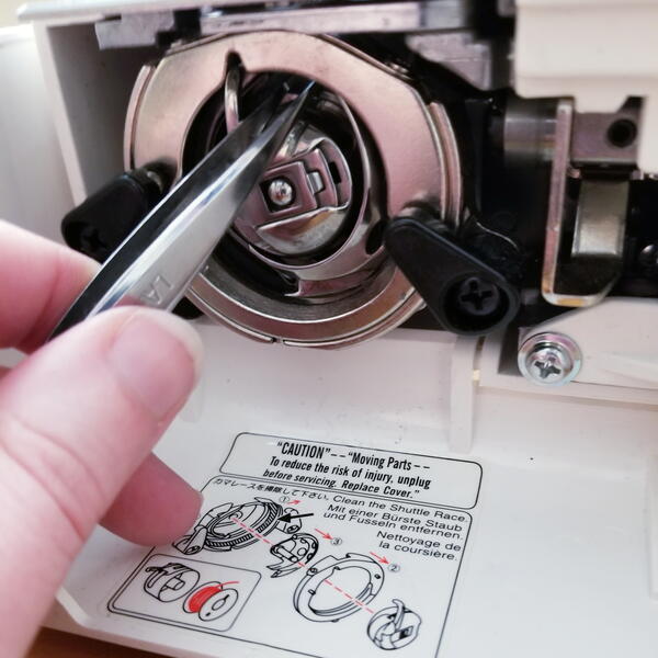 Tweezers reaching inside sewing machine