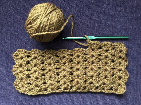 Image shows the start of a shell stitch blanket in gold.