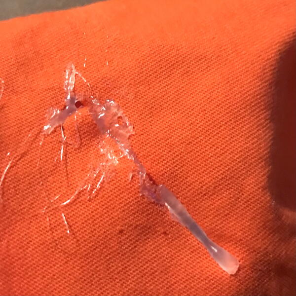 Image shows hot glue applied to the rip on the fabric.