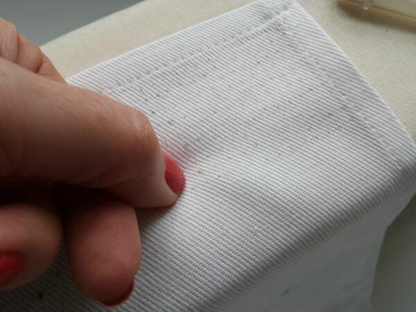 Image shows a person using their nail to help close fabric holes.