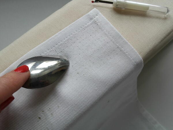 Image shows a person using a spoon to help close fabric holes.
