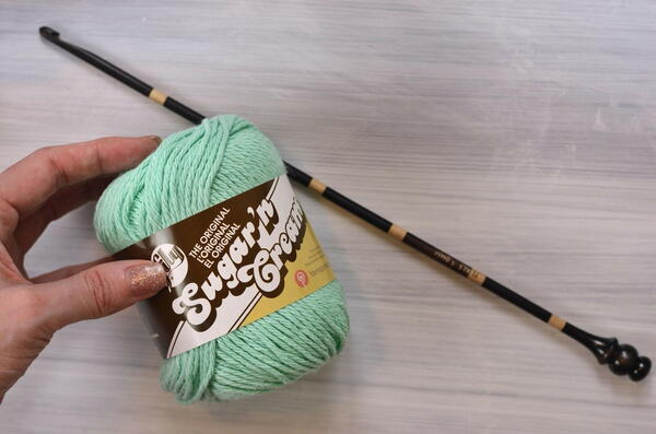 Image shows the Tunisian crochet hook and a ball of yarn.