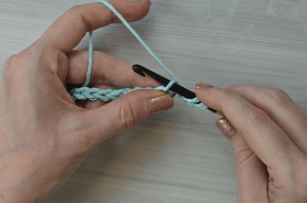 Image shows inserting the hook into the next chain for the Tunisian double crochet piece.