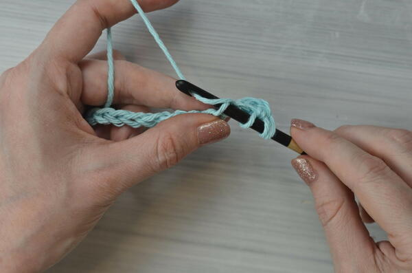 Image shows yarning over for the Tunisian double crochet piece.