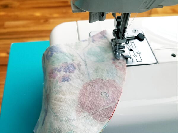 Image shows a sewing machine sewing the curved edge of the DIY mask.
