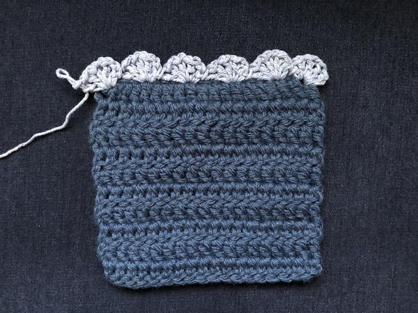 Image shows an example of a finished crochet square and a border on one side crocheted using a different weight of yarn.