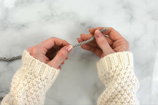 Image shows how to wind a hank of yarn by hand: step 13 showing wrapping the yarn by hand.