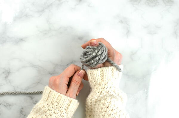 Image shows how to wind a hank of yarn by hand: step 22 showing wrapping the yarn by hand.