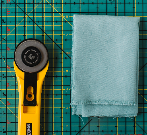 A cutting board, piece of fabric, and rotary cutter