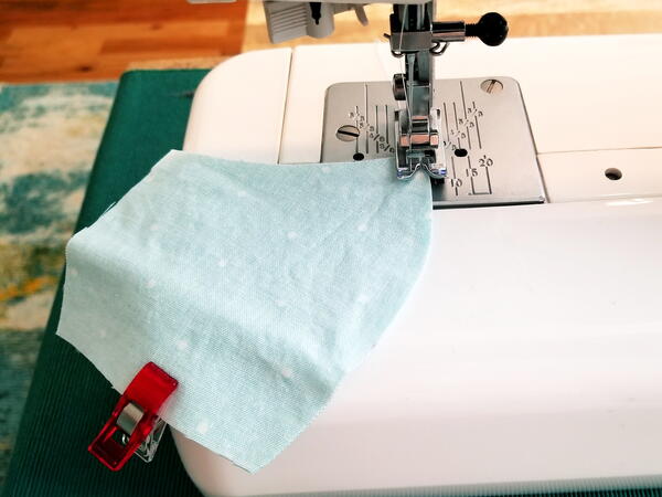 Image shows a sewing machine sewing the curved edge of the DIY mask.