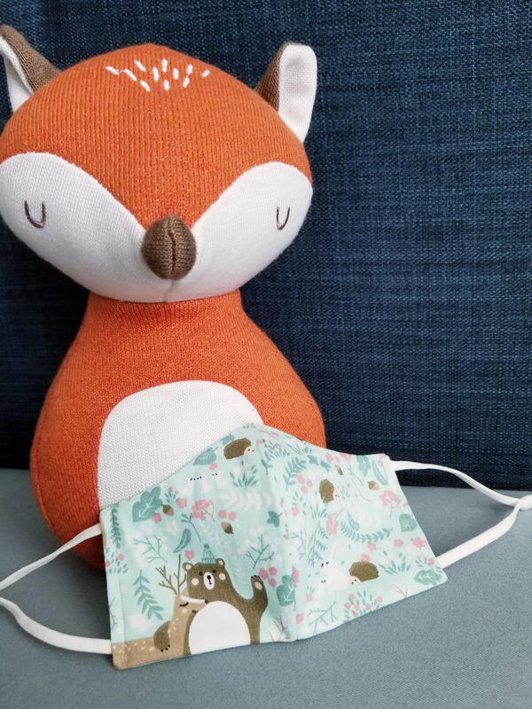 Image shows the finished child size fabric face mask with a fox toy.