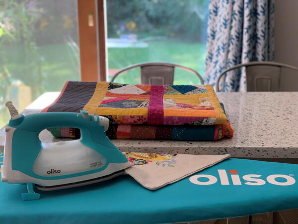 Ironing Tips for Beginners: Oliso iron sitting on an ironing board.