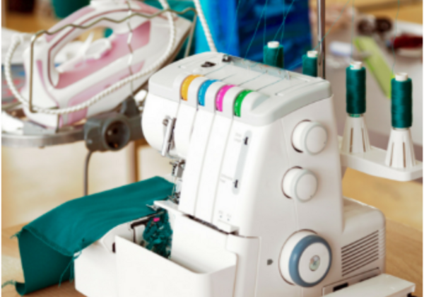Image shows a serger sitting on a sewing table.