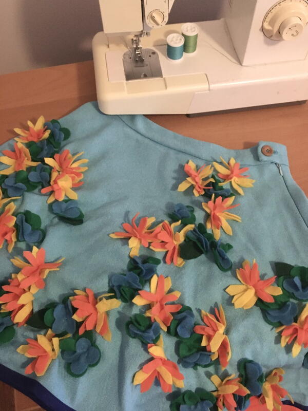 Image shows a sewing machine and a finished skirt adorned with 3D flowers.