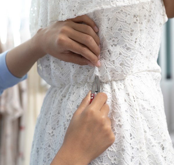 Image shows a person clipping threads on a dress.