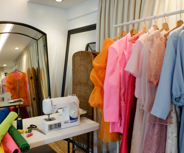 Image shows a sewing room with sewing supplies and finished garments.