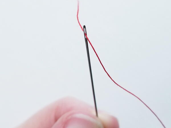 Threading a sewing needle: pulling thread through the eye