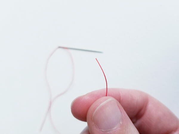 Threading a sewing needle: end of thread