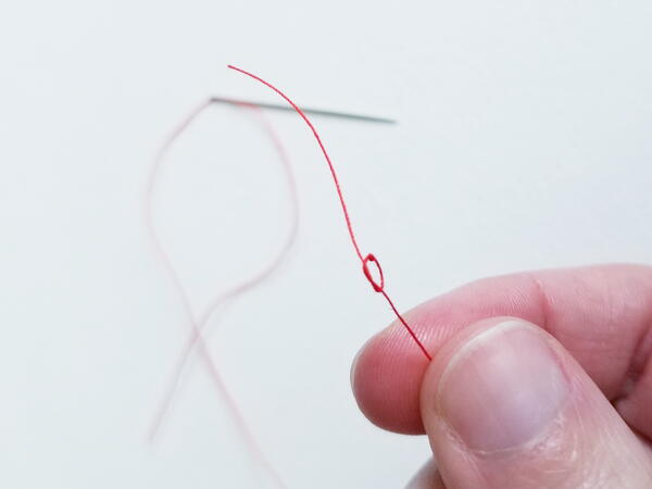 Threading a sewing needle: creating knot for sewing thread