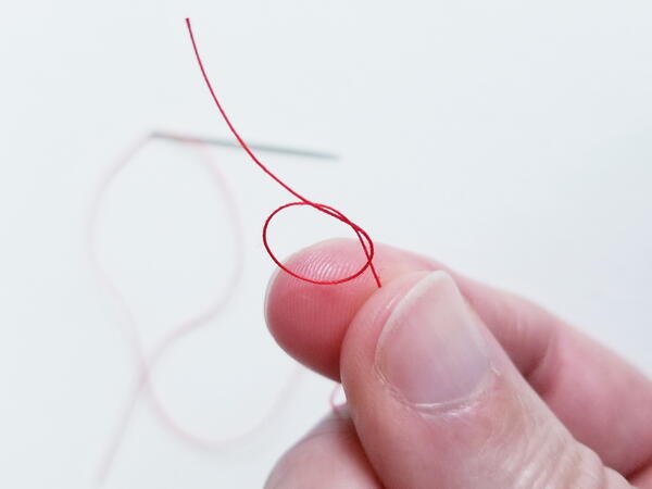 Threading a sewing needle: creating knot for sewing thread